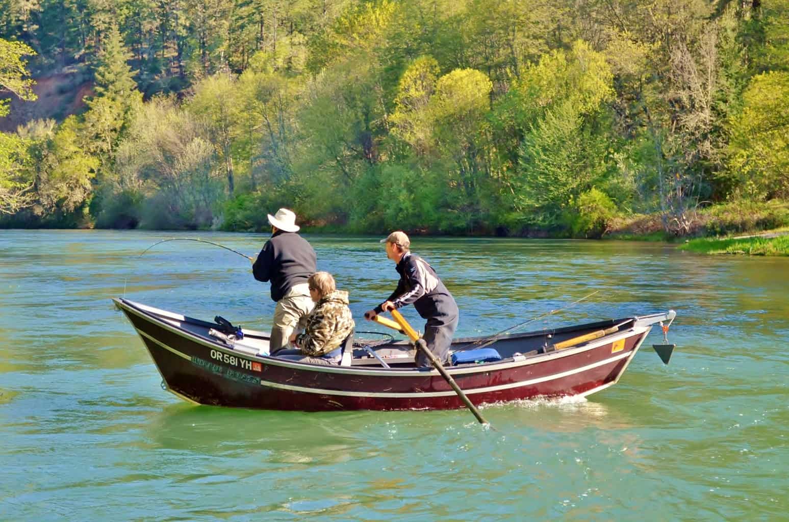 A drift boat with anglers fishing on the rogue river in southern Oregon.