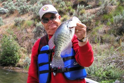 A fisherman holding a crappie caught on brownlee reservoir.