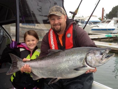 An Angler and a child holding a chinook salmon caught at buoy 10.