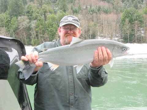 An angler holding a steelhead caught at chetco river.