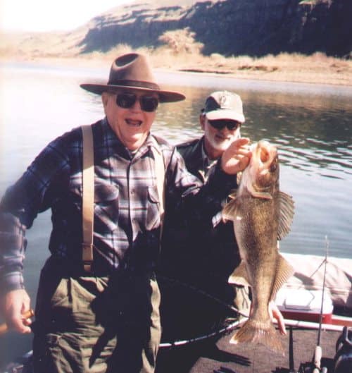 Anglers holding a walleye in a boat.