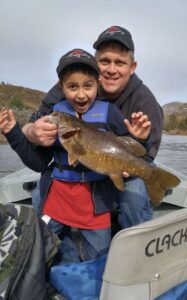 An angler and a child holding a smallmouth bass caught at john day river.