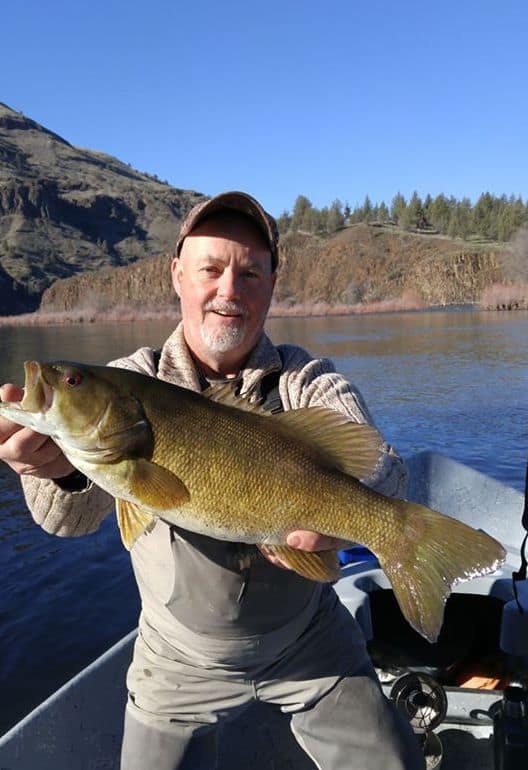 An angler holding a john day river smallmouth bass.