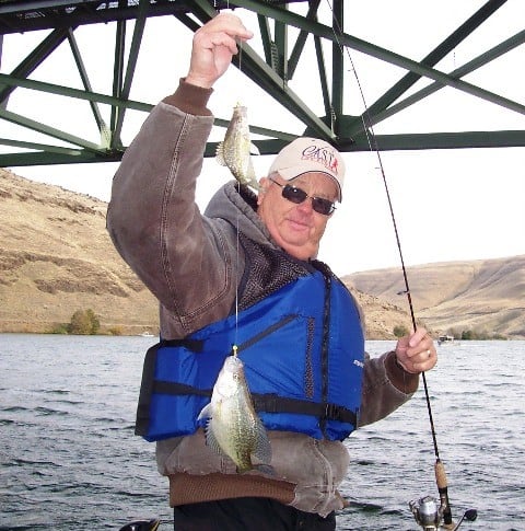 An angler holding a fishing rod with a crappie caught at John Day River.