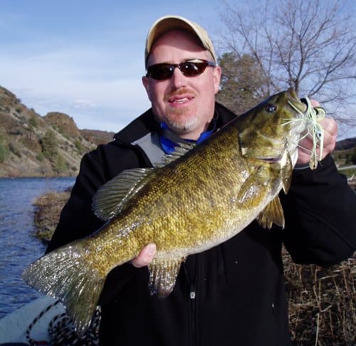 A fisherman holding a bass.