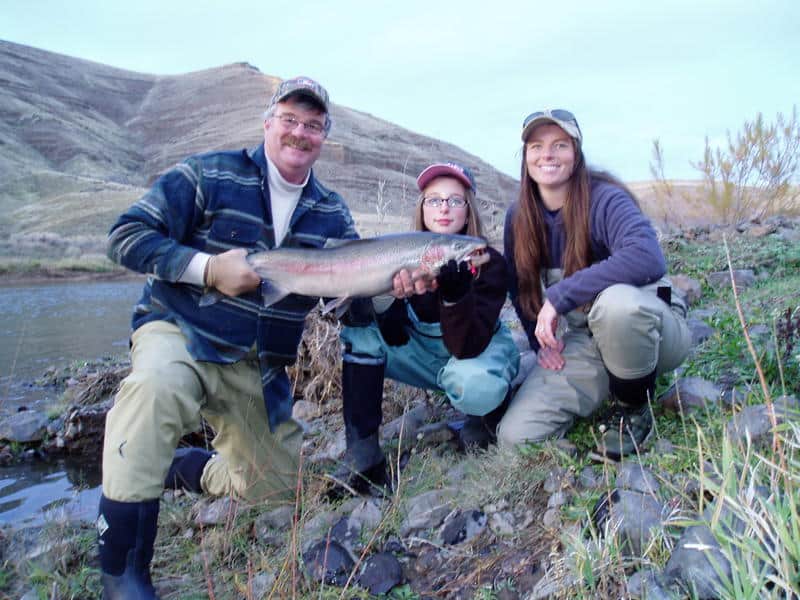 Anglers holding a steelhead caught east of the cascade.