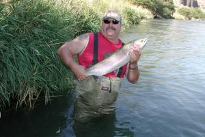 A fisherman holding a large steelhead caught in deschutes river.