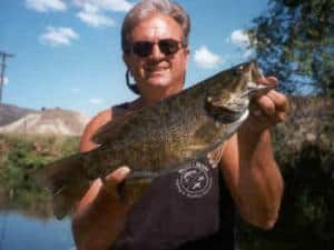 An angler holding a smallmouth bass caught in john day river.