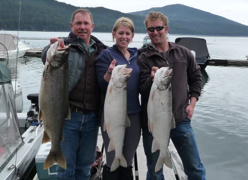 Anglers hold up three large lake trout or mackinaw caught at Odell Lake in Central Oregon.
