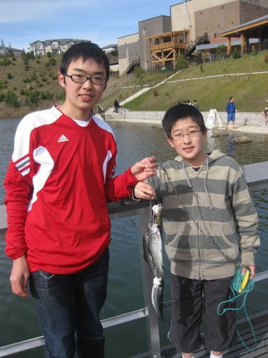Two anglers showcasing caught fish at progress lake.