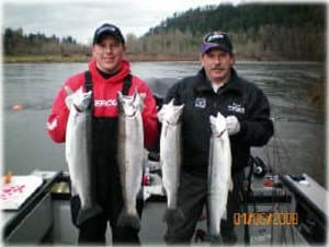 Anglers holding steelhead caught at sandy river.