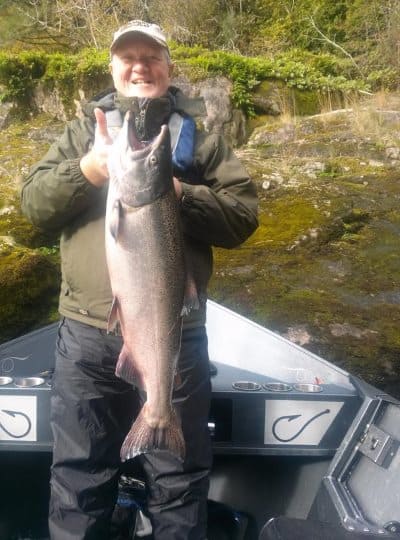 An angler holding a fall chinook caught in siuslaw river.