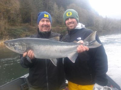 Two anglers hold a siuslaw salmon.