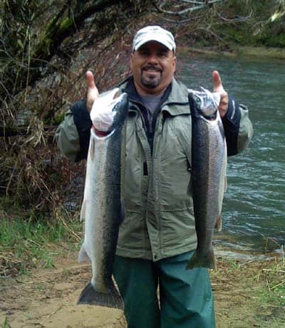 An angler holding two winter steelhead caught at siuslaw river.