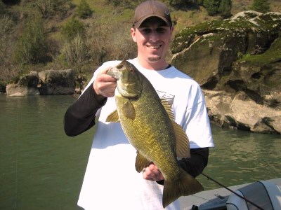 An angler holding a smallmouth bass caught at umpqua river.