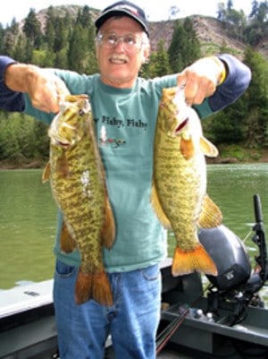An angler holding a couple of very nice smallmouth bass caught in the umpqua river.