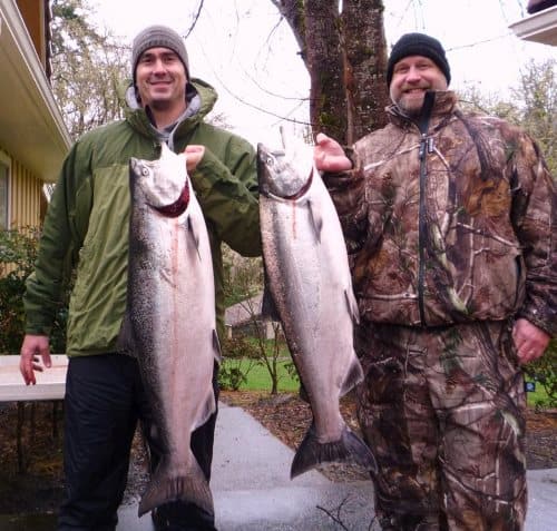 Two anglers holding fish caught at umpqua river..