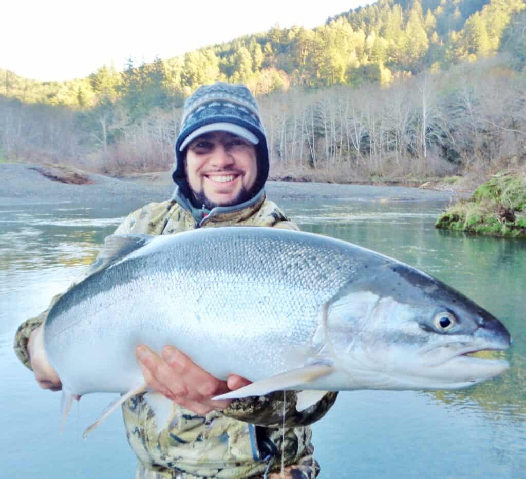 An angler holding a winter steelhead caught at sixes river.