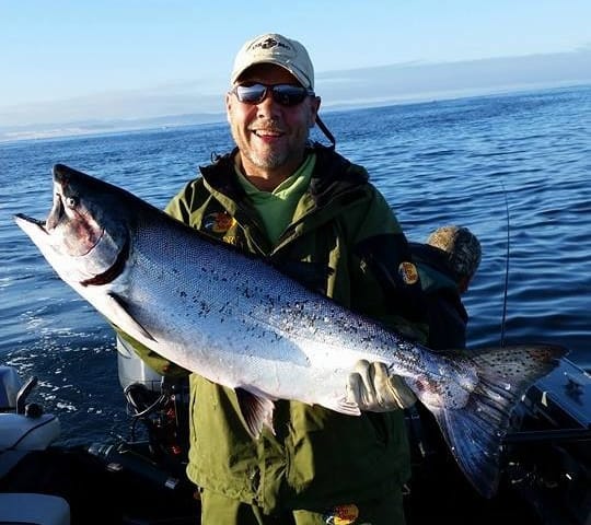 A happy angler holds a large salmon caught at Winchester Bay on the Oregon Coast.