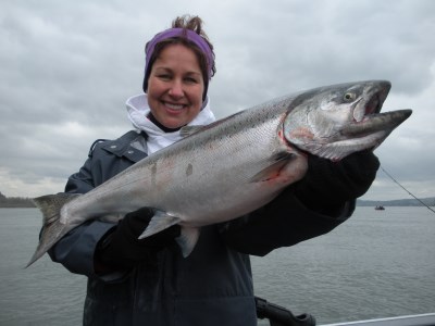 A woman holds a salmon caught at Buoy 10.