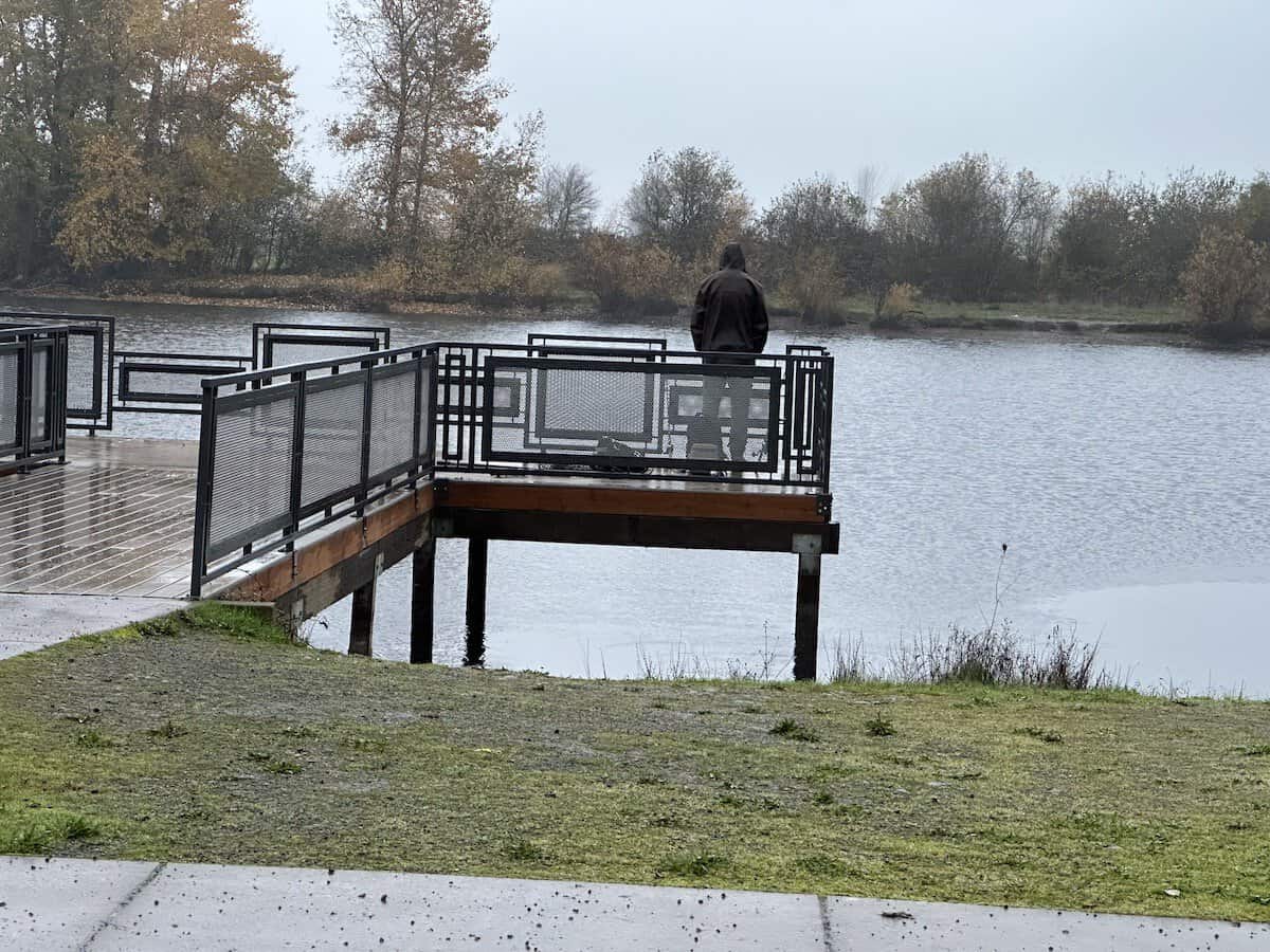 Angler on a fishing dock watches his fishing poles for a trout to bite at Junction City Pond.