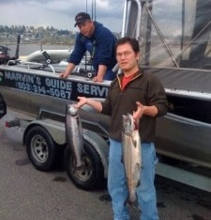 A fishing guide's client holds up two spring Chinook salmon caught in the Willamette River in Portland.