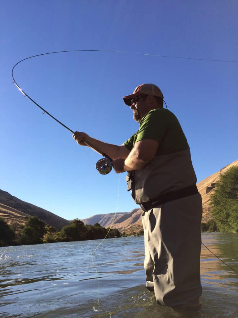 A man casting a fly rod into the deschutes river.