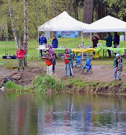 Plenty of people fishing at Canby Pond during a family fishing event.