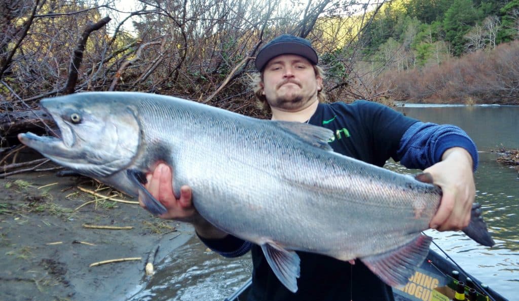 An angler holding a salmon caught at sixes river.