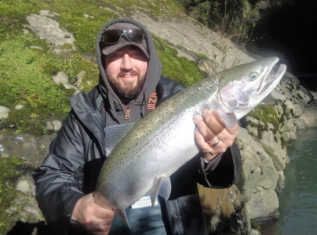 An angler holding a salmon caught at sixes river.