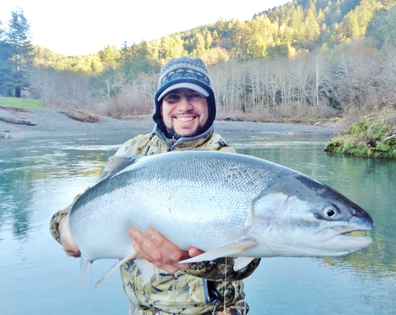 An angler holding a steelhead caught at upper sixes river.