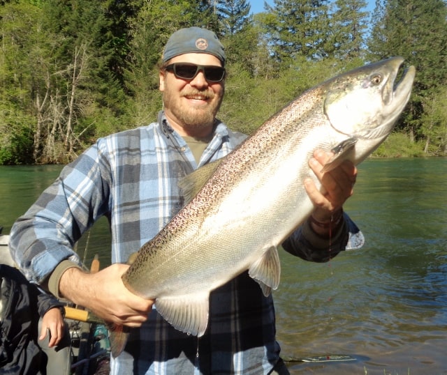 An angler holding a salmon caught at rogue river.