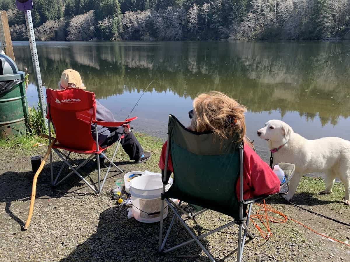 Two women and a dog relax while fishing for trout at Big Creek Reservoir 2 near Newport, Oregon.