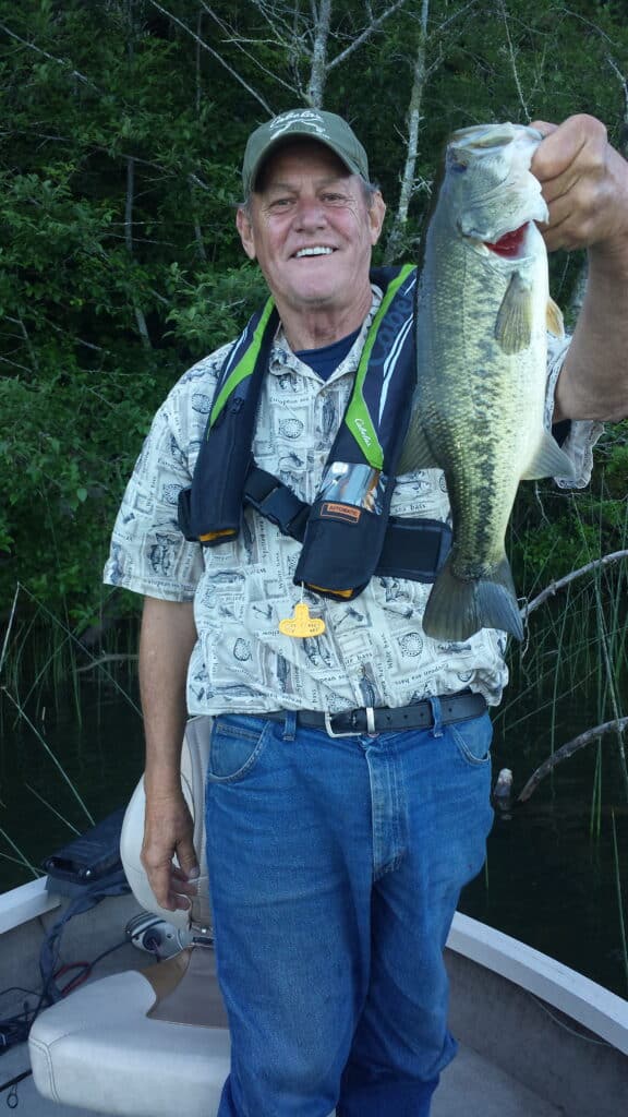 An angler holding a largemouth bass caught in siltcoos lake.