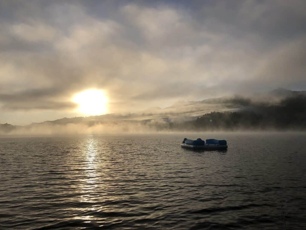 A boat with a scenic view of triangle lake in the background.