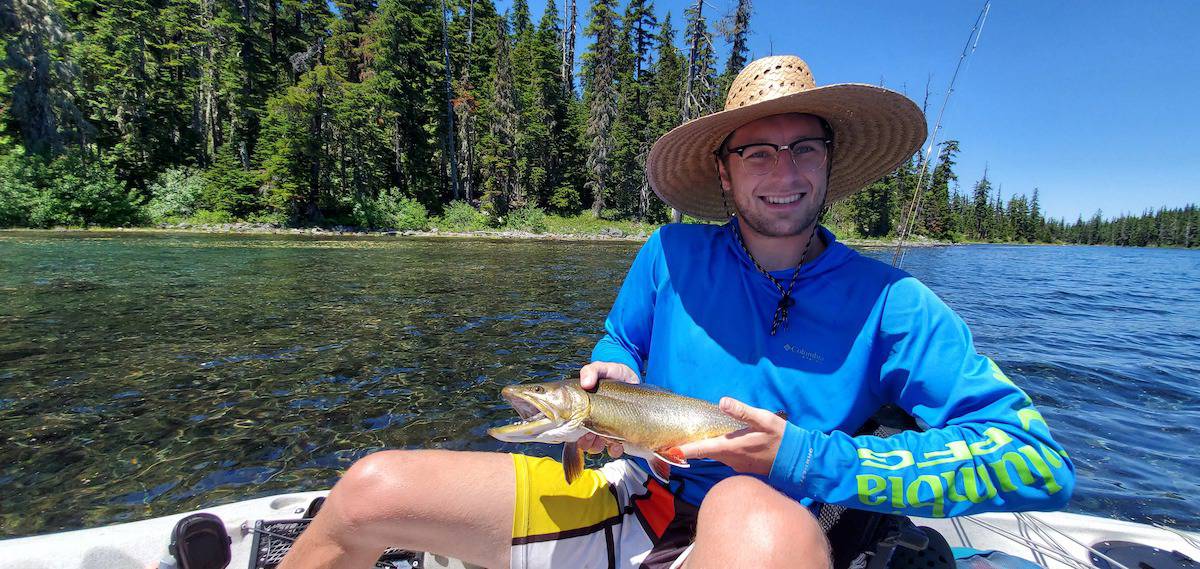 Angler in a kayak holding a brook trout caught at Waldo Lake in Oregon.