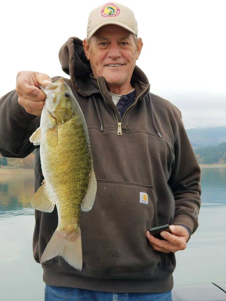 An angler holding a smallmouth bass caught at hagg lake.