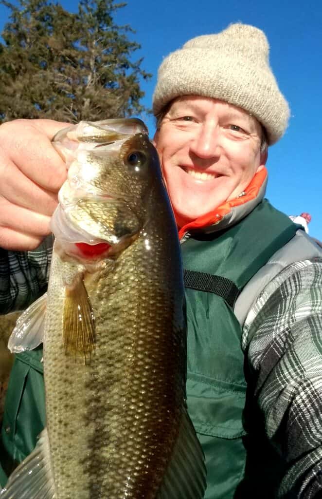 An angler holding a largemouth bass caught at Cullaby Lake on the northern Oregon coast.