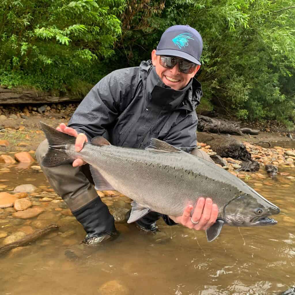 An angler holding a salmon caught fly fishing in the Hoh River.