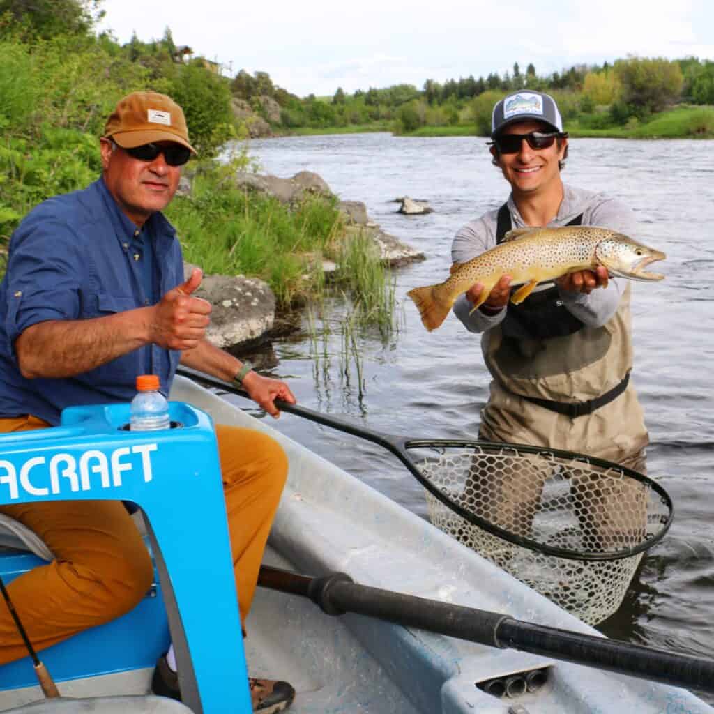 Two anglers showcasing their caught fish with one holding a net.