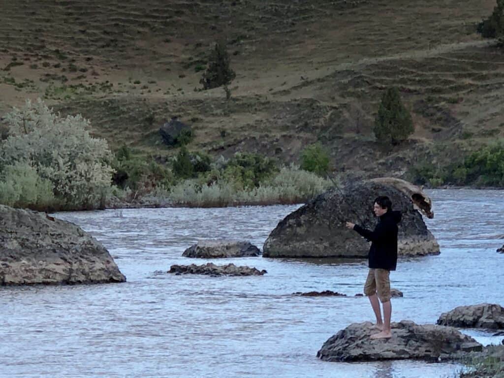 A barefoot boy casts for smallmouth bass during a multi-day float of the John Day River in Oregon.