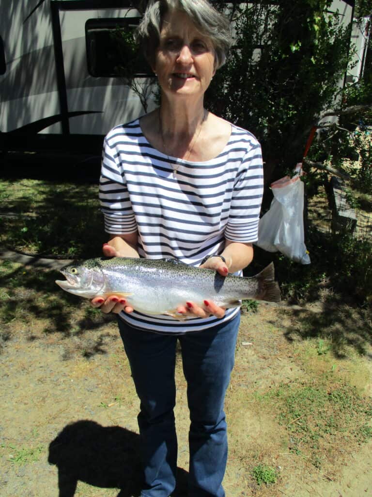A woman holds a large trout she caught while fishing at Siltcoos Lake.