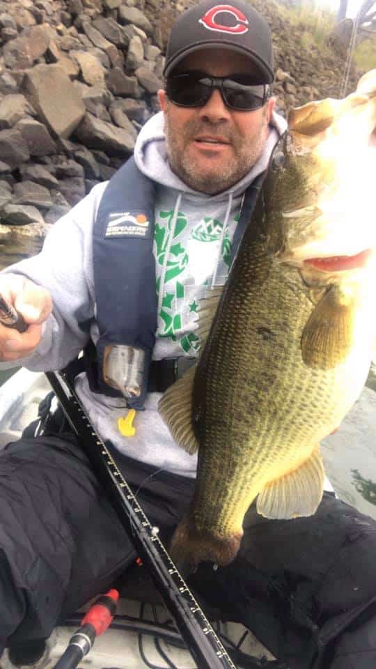 An angler holding a largemouth bass caught at Rowland Lake.
