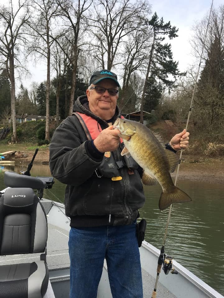 An angler holding a trophy-sized smallmouth bass caught in the Clackamas River section of the Willamette River.