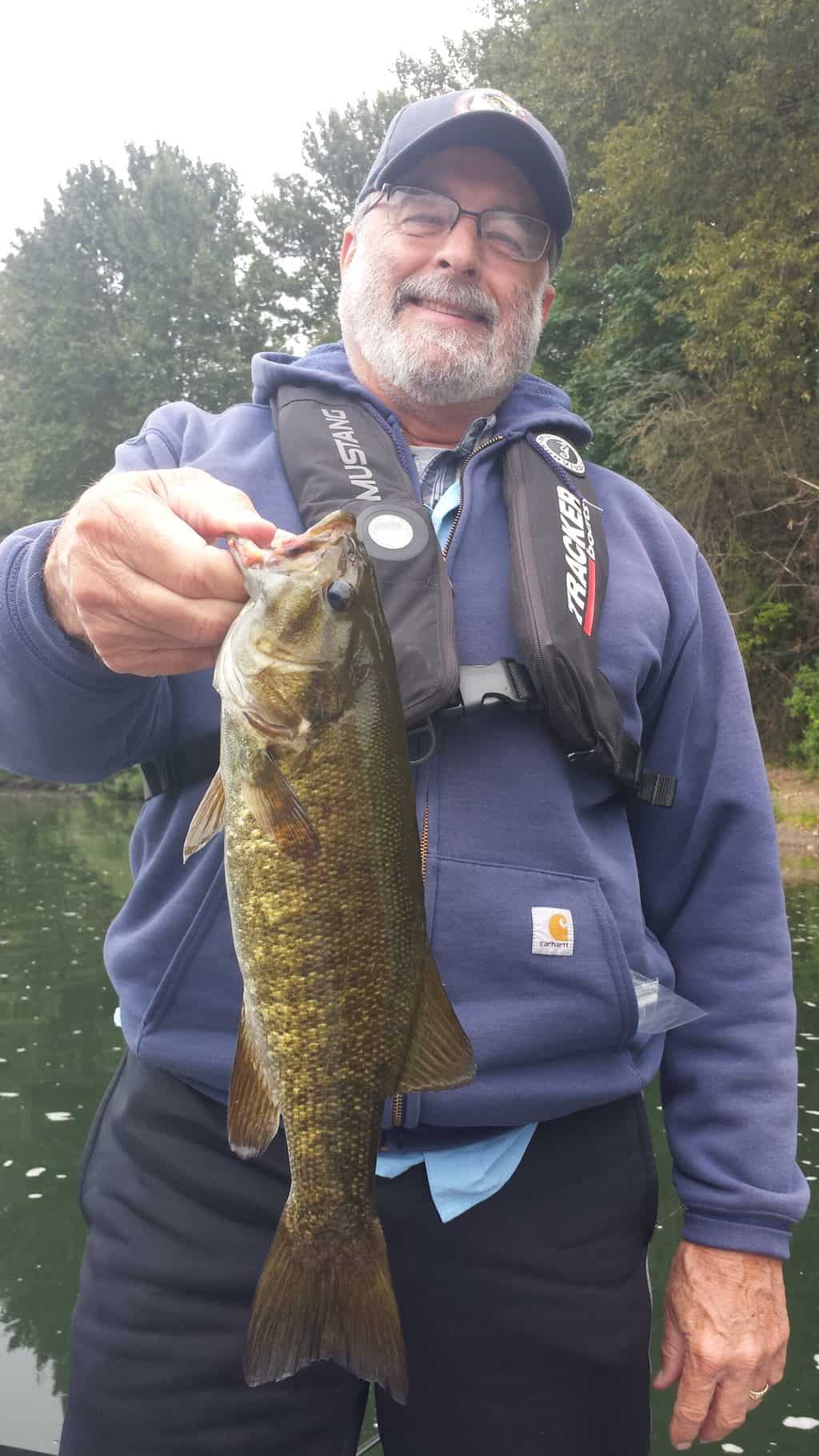 An angler holding a smallmouth bass caught in the Willamette River near Newberg in Yamhill County.