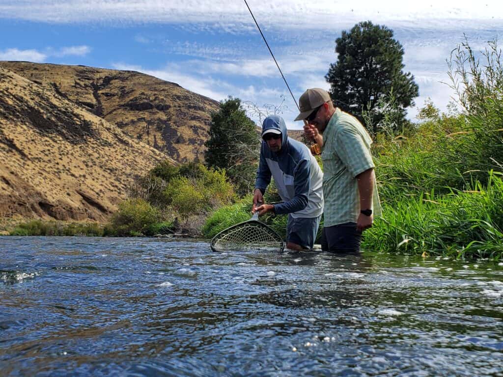 Anglers netting a trout on the yakima river in washington.