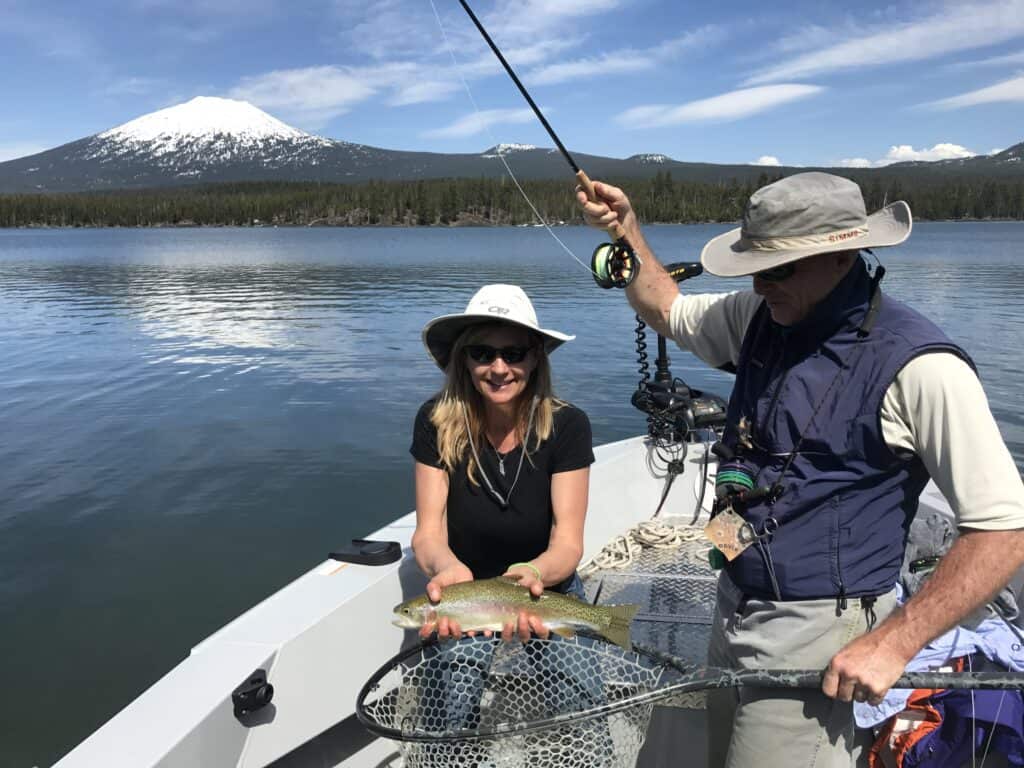 A woman holding a trout caught at lava lake.