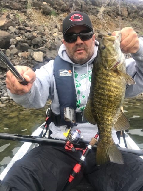 An angler holding a smallmouth bass caught at rowland lake, washington.