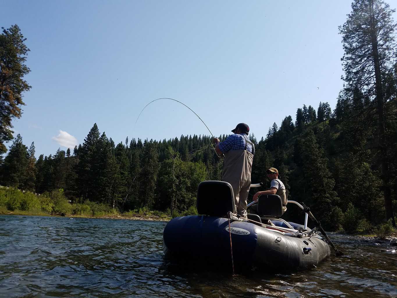 Anglers on a boat fly fishing and fighting a trout on the Naches River.