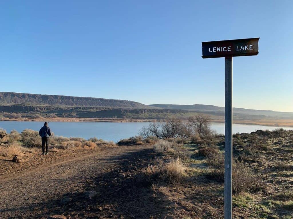 A sign for lenice lake and a scenic view in the background.